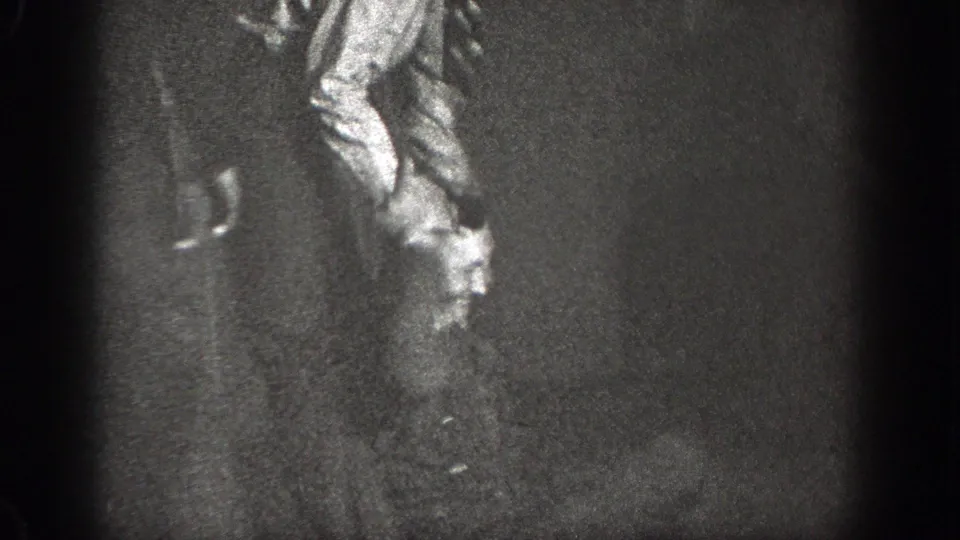 A light-shirted adult appears partly obscured next to a dark-clothed figure in grainy 1939 Chelan home-movie footage.