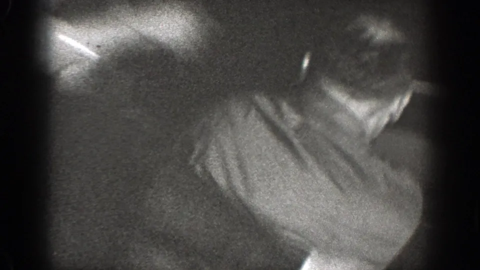 A man in a light shirt appears in a soft, unstable close-up as the Chelan home-movie altercation moves out of clear view.