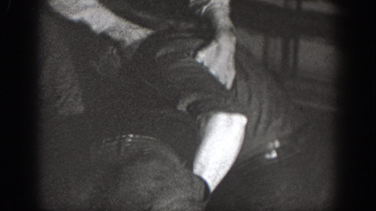 1939 Chelan home-movie frame showing men in a dim interior around a close physical struggle.