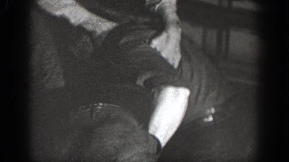 1939 Chelan home-movie frame showing men in a dim interior around a close physical struggle.