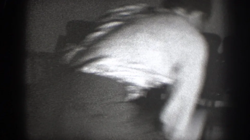 1939 Chelan frame with a light-shirted man bending forward during a fast, unclear indoor altercation.