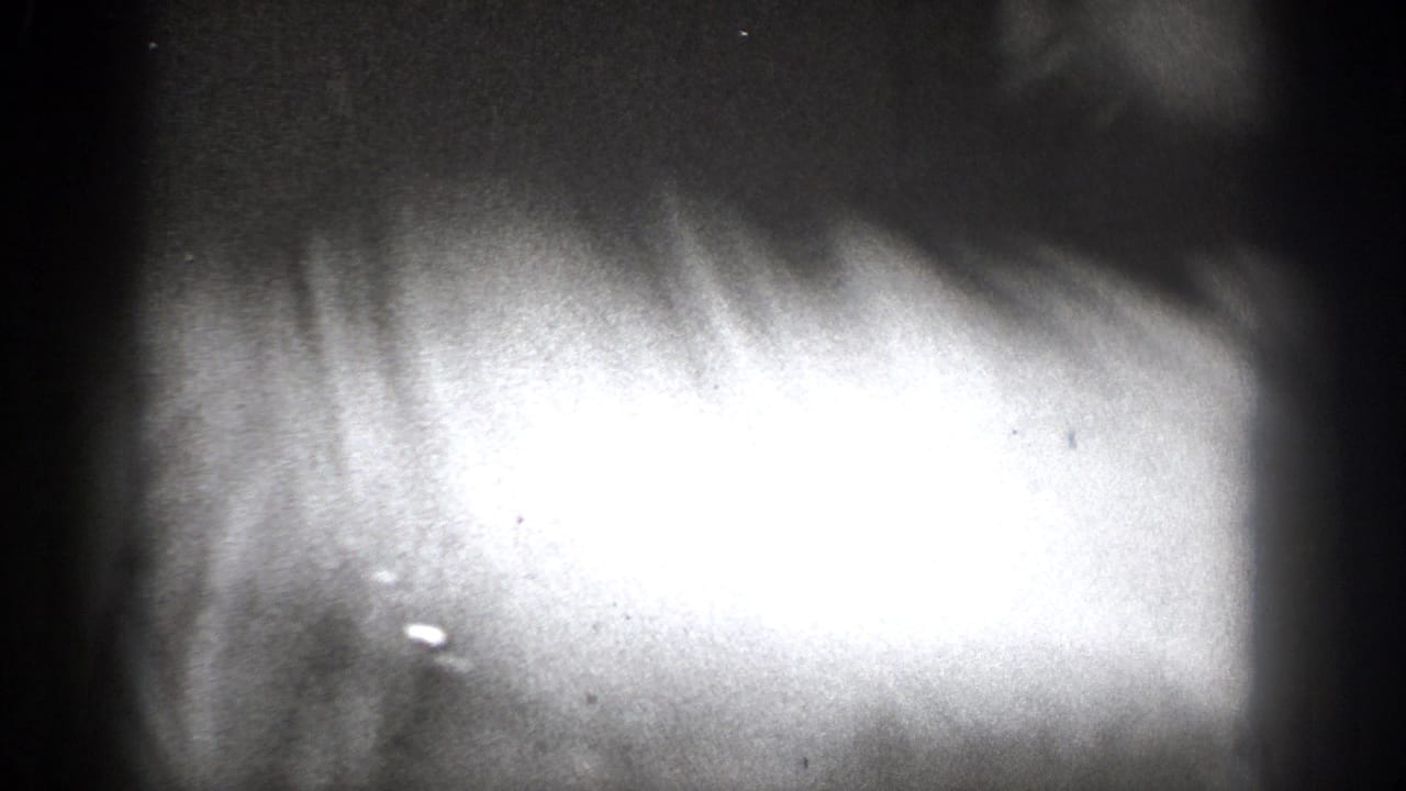 Grainy 1939 Chelan home-movie frame with an overexposed close foreground shape and dark interior edges.