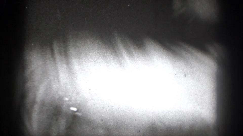Grainy 1939 Chelan home-movie frame with an overexposed close foreground shape and dark interior edges.