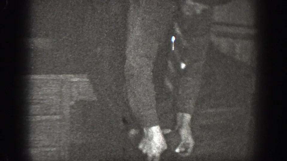A 1939 Chelan home-movie frame shows a man in a button-up shirt and trousers standing barefoot indoors.
