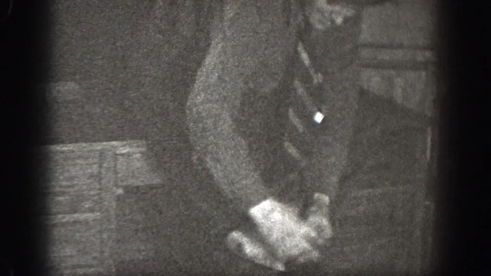In 1939 Chelan, Washington footage, a man in a dark suit sits indoors with his hands near his lap in soft, grainy light.