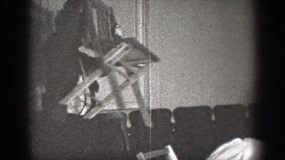 A blurred figure moves beside an interior wall during the playful 1939 Chelan home-movie scuffle.