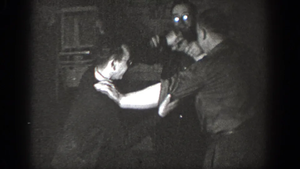 Two adult men appear to wrestle or separate playfully inside a private room in the Chelan, Washington 1939 footage.