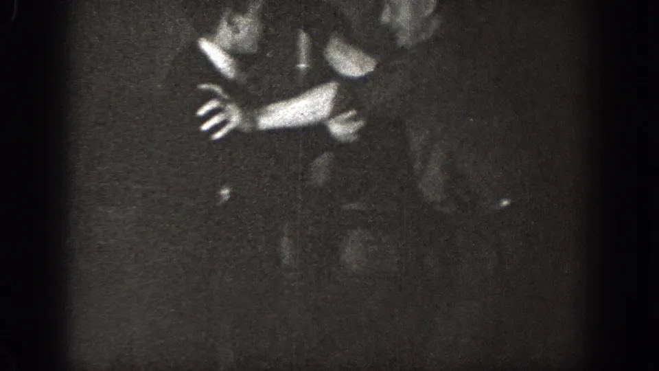 A close, grainy 1939 Chelan frame shows two adult men in formal clothing with arms raised or gripping during a tense interaction.