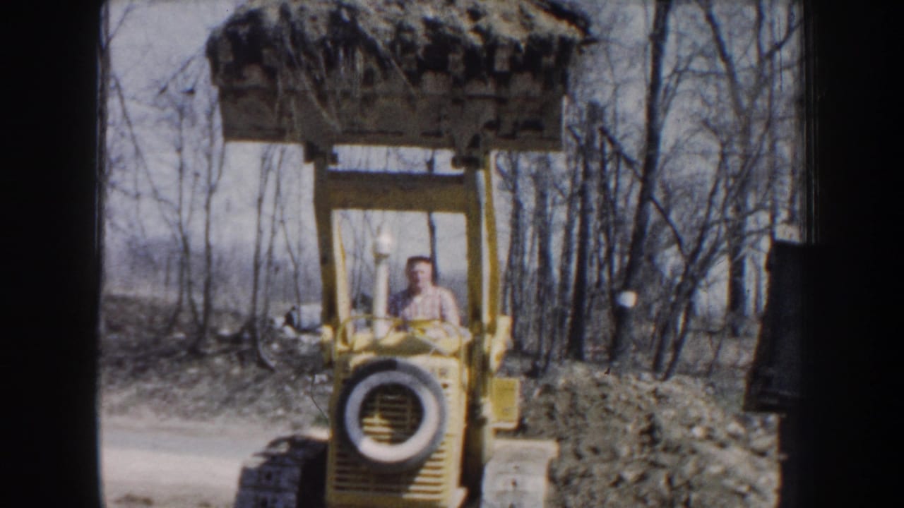 Yellow front-end loader faces the camera with a man seated behind the controls.