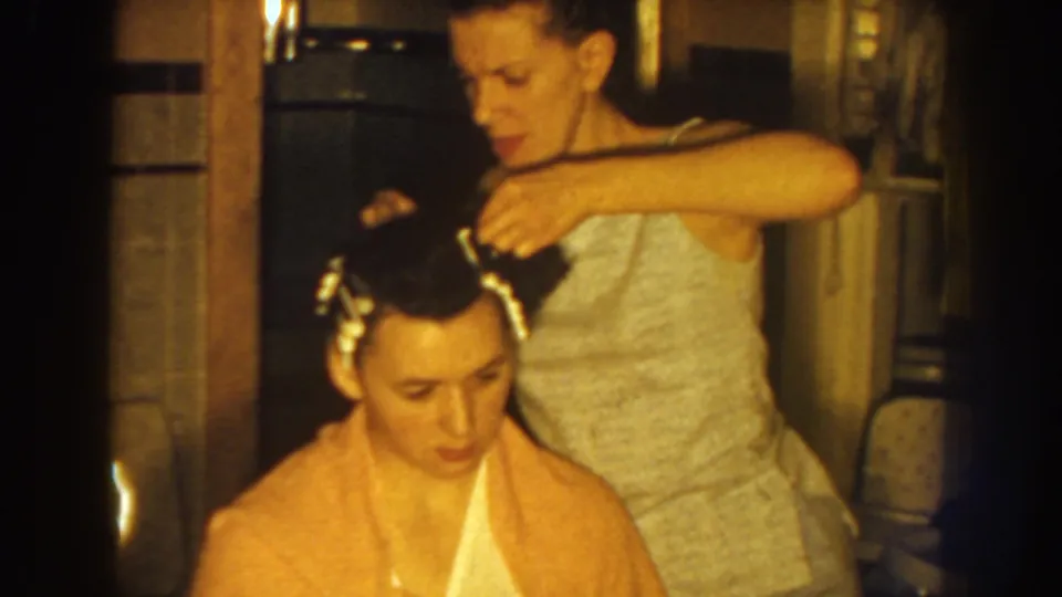 The mother finishes another adjustment to her daughter's hair rollers during an intimate 1959 Nebraska wedding-preparation moment.
