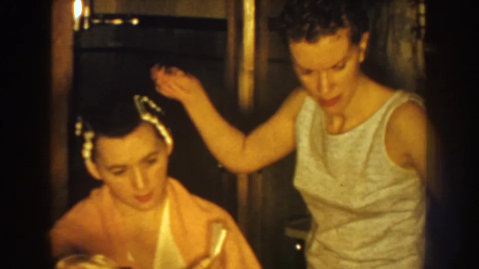 The seated woman with white rollers remains still while the stylist works beside her in a 1959 Nebraska home interior.