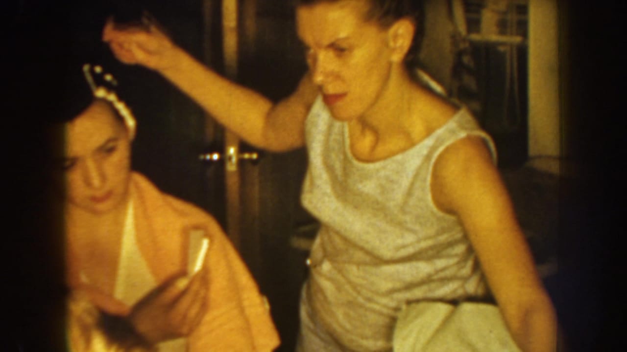 Older sister reaches over younger sister's hair while the seated younger sister holds a comb.