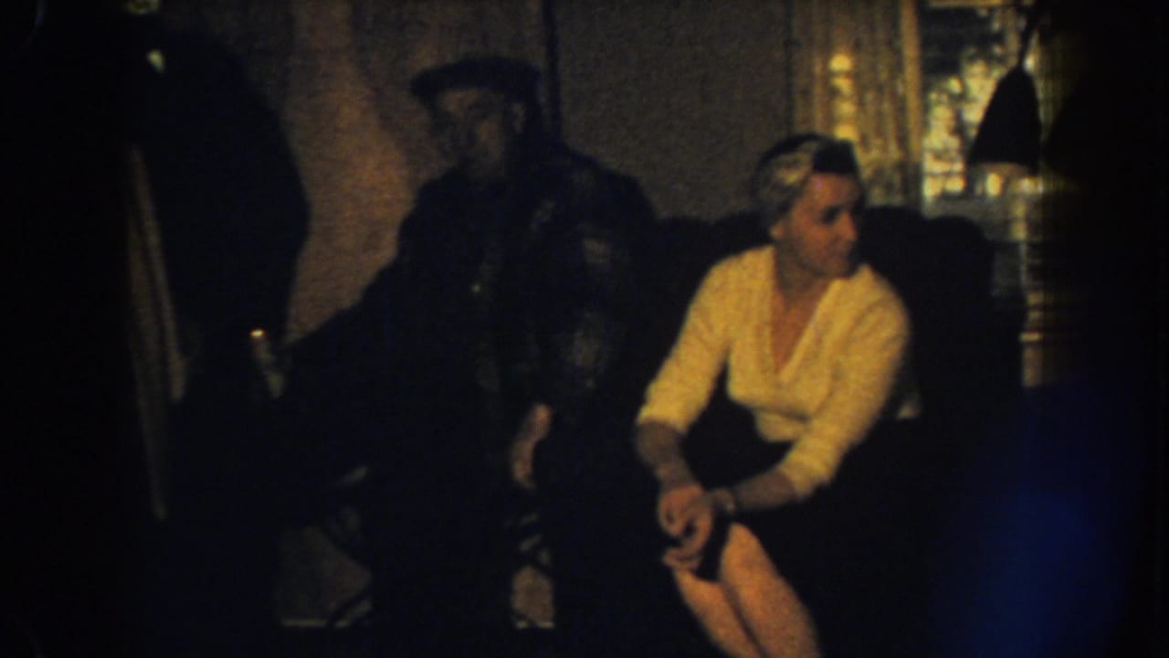 Woman in a yellow sweater sits on a couch with a man in shadow behind her.