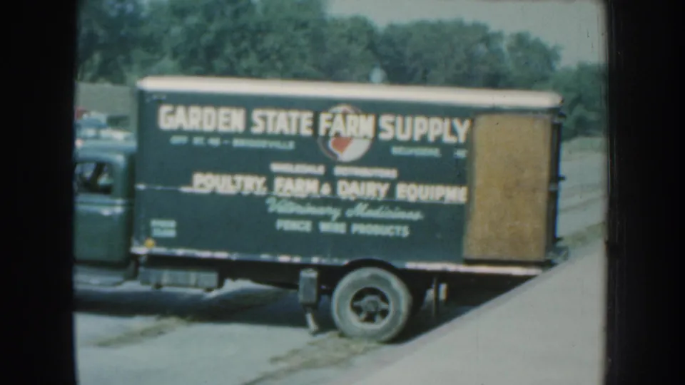 1959 Nebraska 8mm frame showing a Garden State Farm Supply delivery truck with farm and dairy equipment lettering.