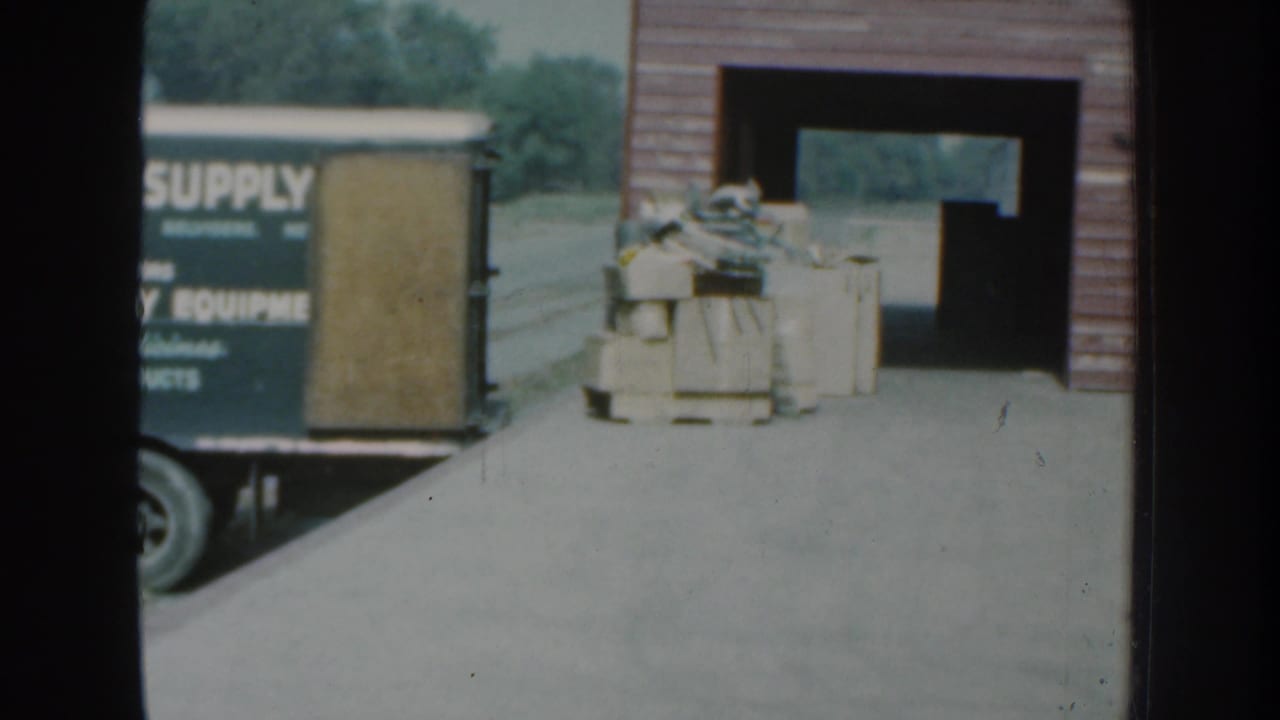 Supply van and crates remain beside the open wooden building.