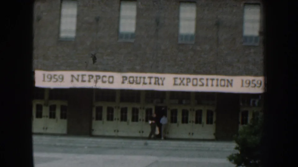 1959 Nebraska frame showing the NEPPCO Poultry Exposition banner across a brick exhibition hall entrance with people near the doors.