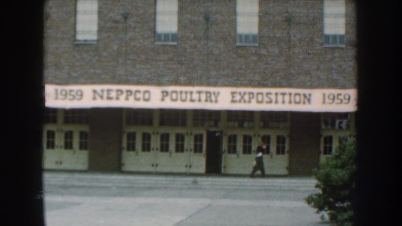 Banner over a brick building entrance with a man walking along the sidewalk.