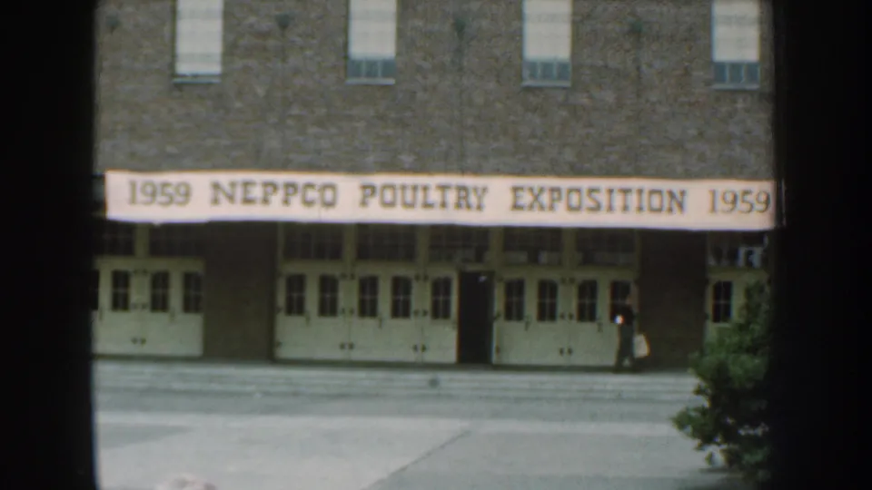 Nebraska 1959 home-movie frame showing the NEPPCO Poultry Exposition entrance as a person moves near the right side of the building.