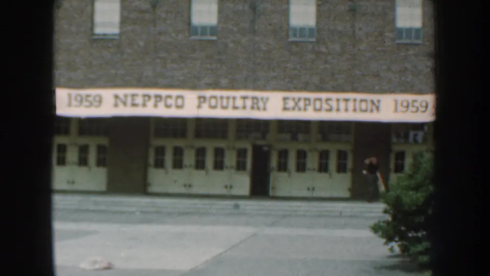 Nebraska 1959 8mm frame of the NEPPCO Poultry Exposition entrance, with the banner centered and a person partly visible at the right edge.