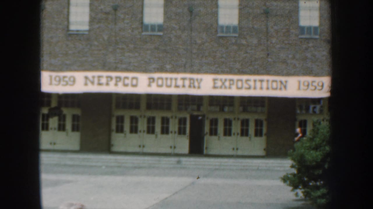 1959 Nebraska frame centered on the NEPPCO Poultry Exposition banner above a brick building entrance.
