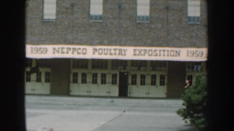 1959 Nebraska frame centered on the NEPPCO Poultry Exposition banner above a brick building entrance.