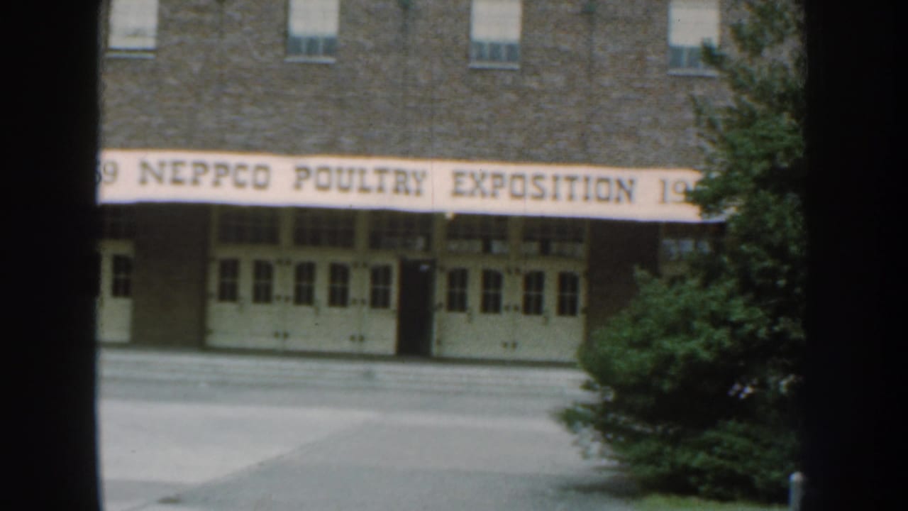 Brick building entrance with a NEPPCO Poultry Exposition banner and dark foreground bars.