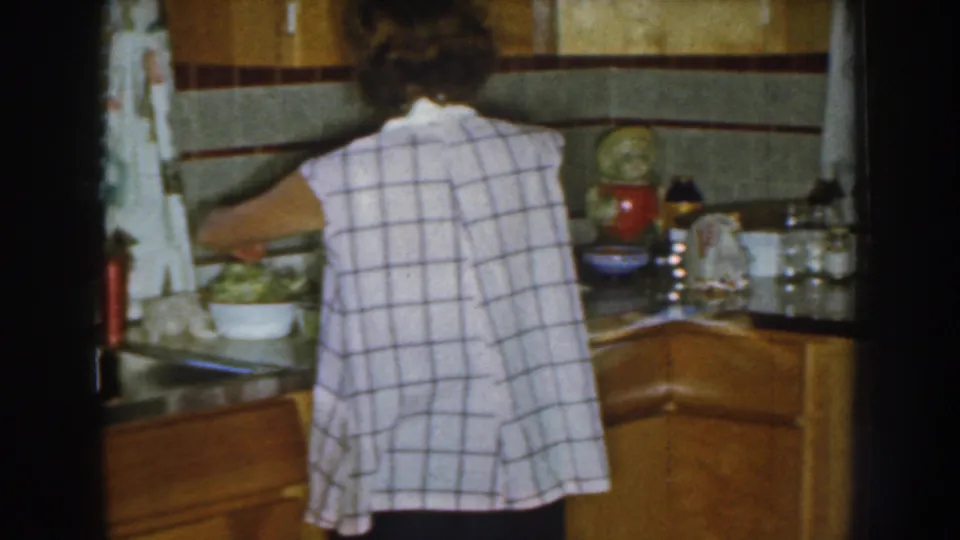 A woman works beside a bowl and cookware in a Nebraska kitchen, with wood cabinets and countertop items visible.