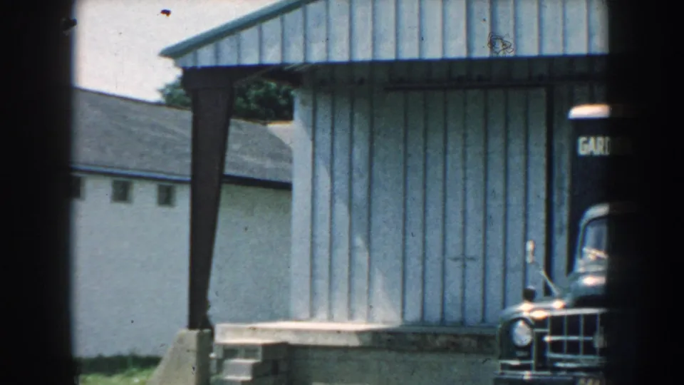 1959 Nebraska frame showing the corrugated building and the edge of a Garden State Supply Co truck.