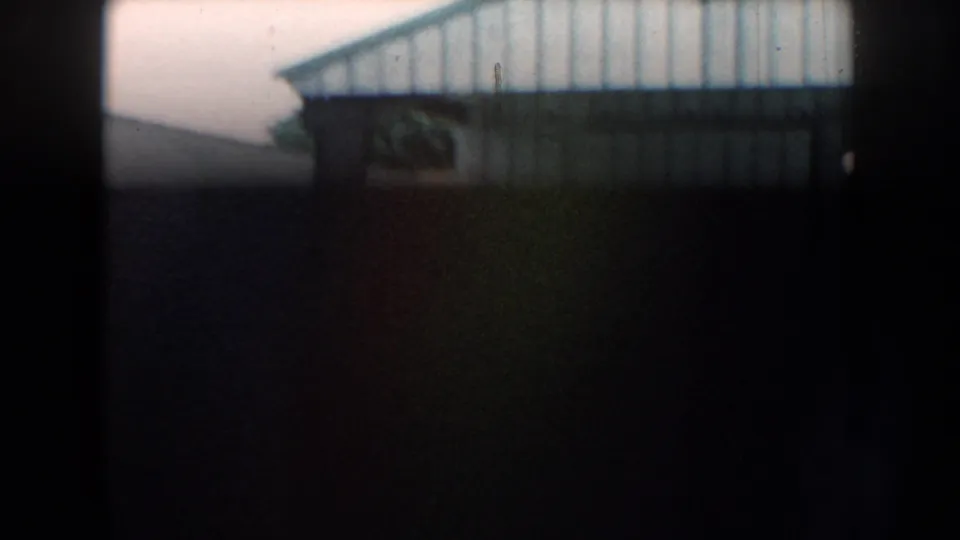 1959 Nebraska 8mm frame with the building and truck mostly obscured by dark exposure and framing.