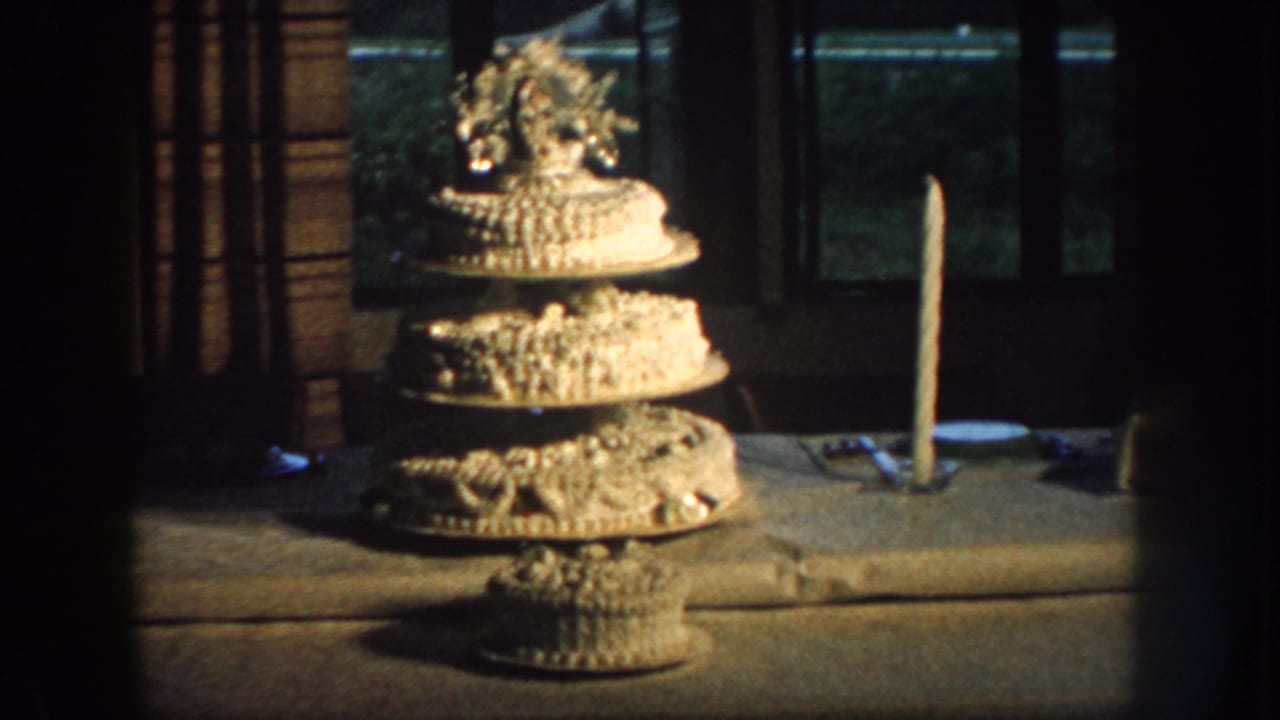 Close view of a decorated three-tier wedding cake displayed indoors or on a sheltered table in 1959 Nebraska footage.