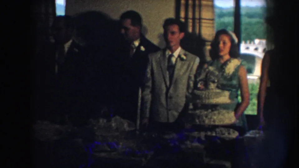 Nebraska 1959 reception frame with a dark foreground figure partially obscuring formal guests and the tiered cake.