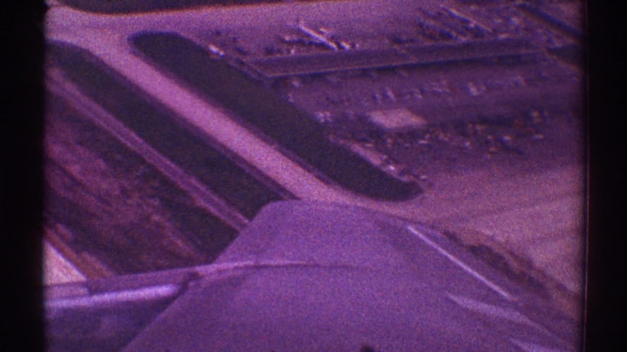 Aircraft wing and engine above airport runways seen through a window.