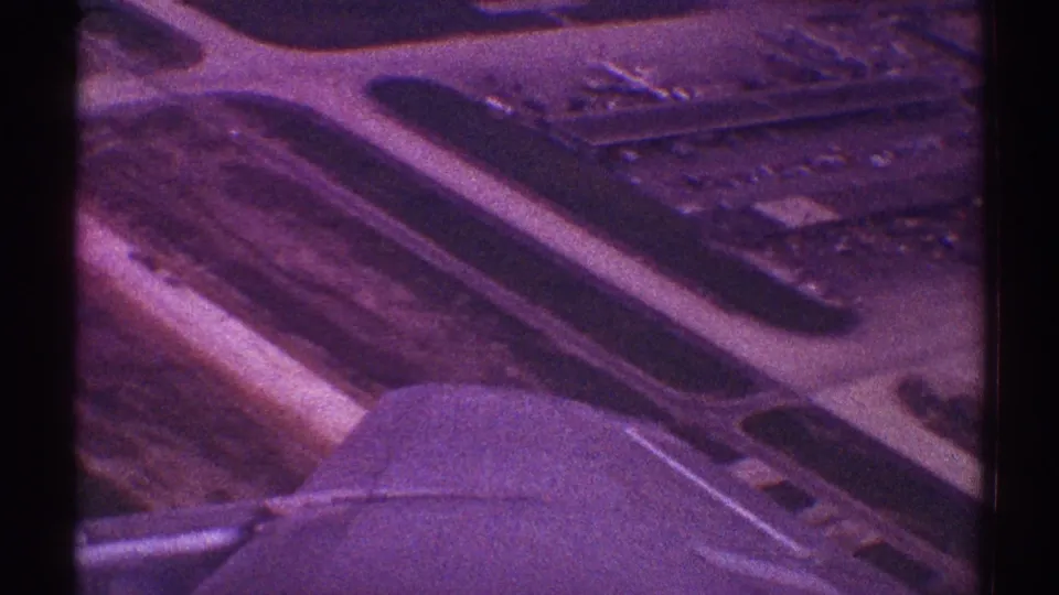Passenger-window view from a 1969 Los Angeles flight, showing the aircraft wing, engine, runways, and terminal-area structures below.
