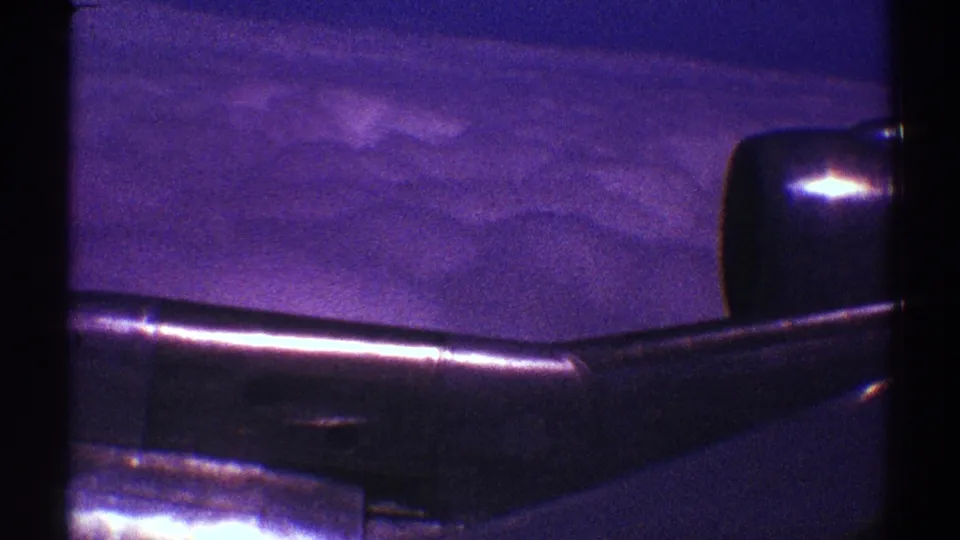 1969 Los Angeles flight view with the aircraft wing and engine silhouetted against blue-purple sky and clouds.