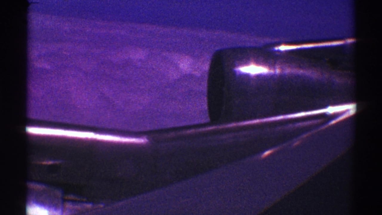 Airplane wing and jet engine seen through a dark window edge with hazy terrain below.