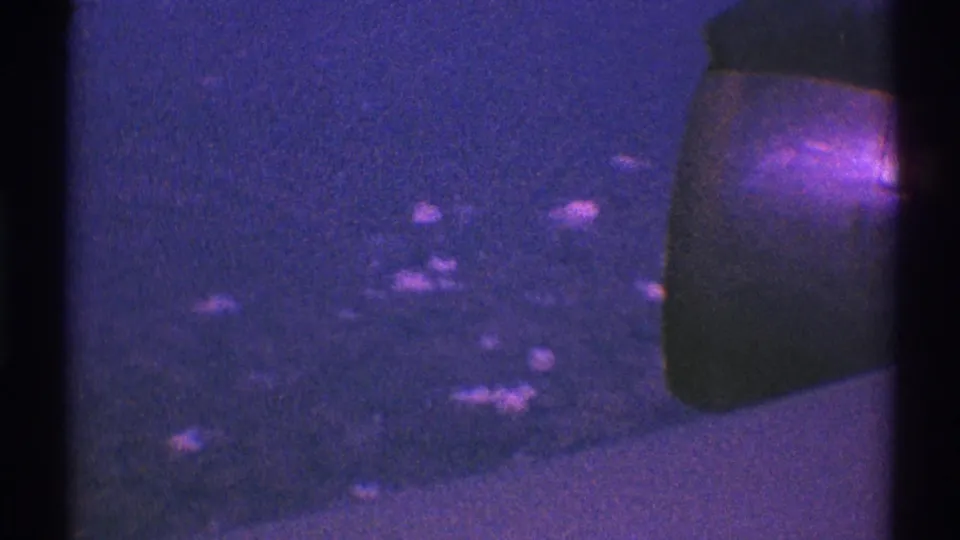 1969 Los Angeles 8mm frame with an abstract night-driving view, scattered reflected lights, and a visible vehicle edge at right.