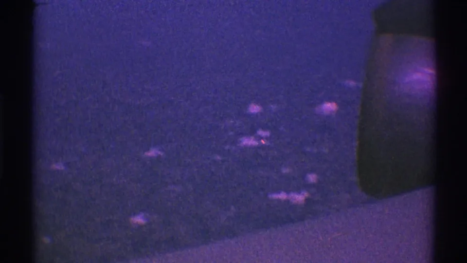 1969 Los Angeles 8mm frame showing a low-light car-side perspective with faint reflections and strong vintage grain.
