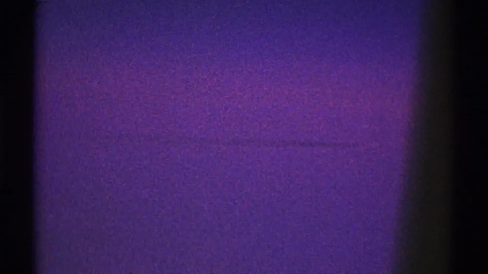1969 8mm Los Angeles home-movie frame with purple exposure, dark window edge, and a faint horizontal mark across the view.