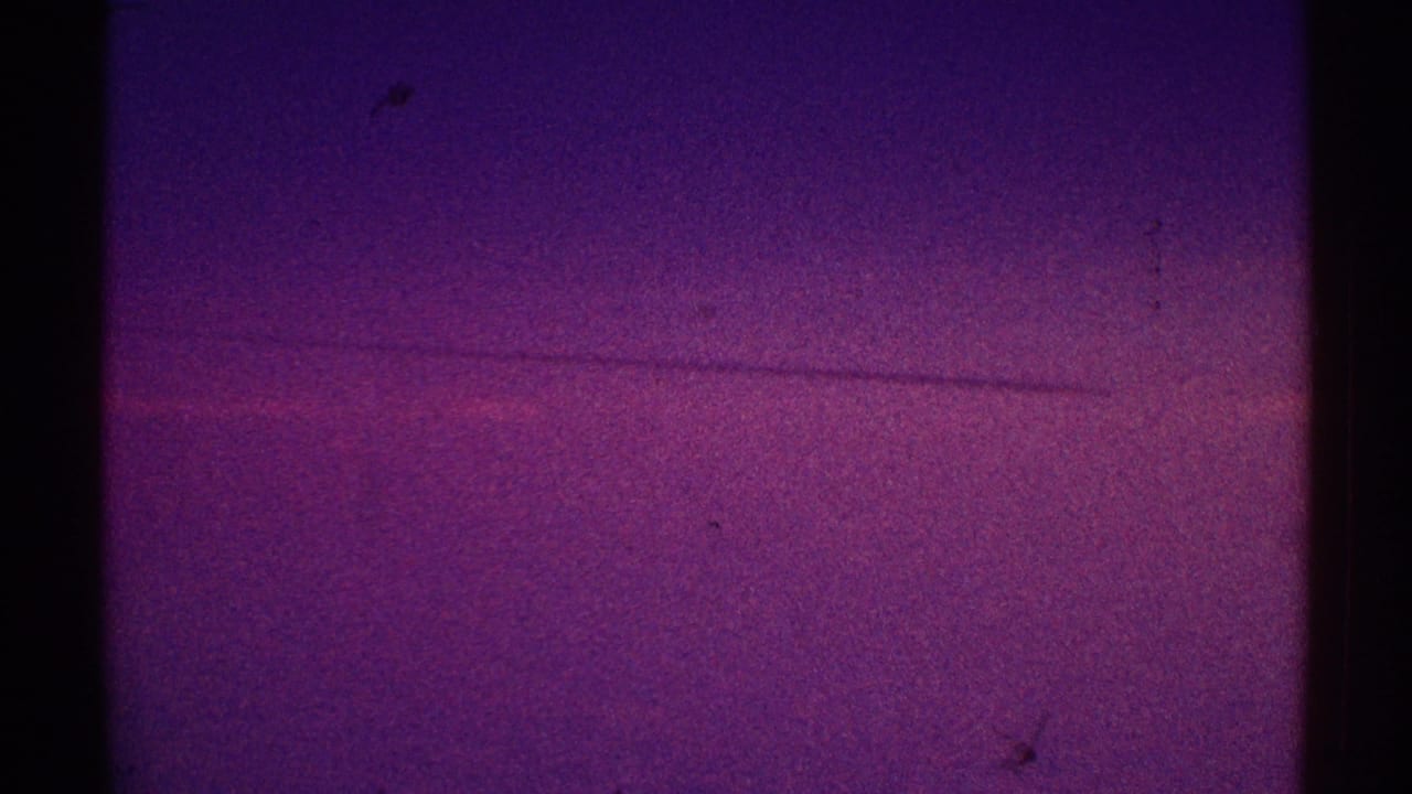 Purple night sky with faint horizontal streaking, grain, dust, and film-edge darkness.