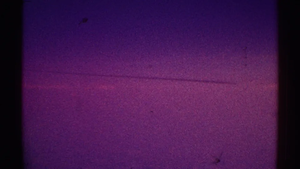 1969 Los Angeles 8mm frame showing a dark purple night sky with a faint horizontal mark and visible film grain.