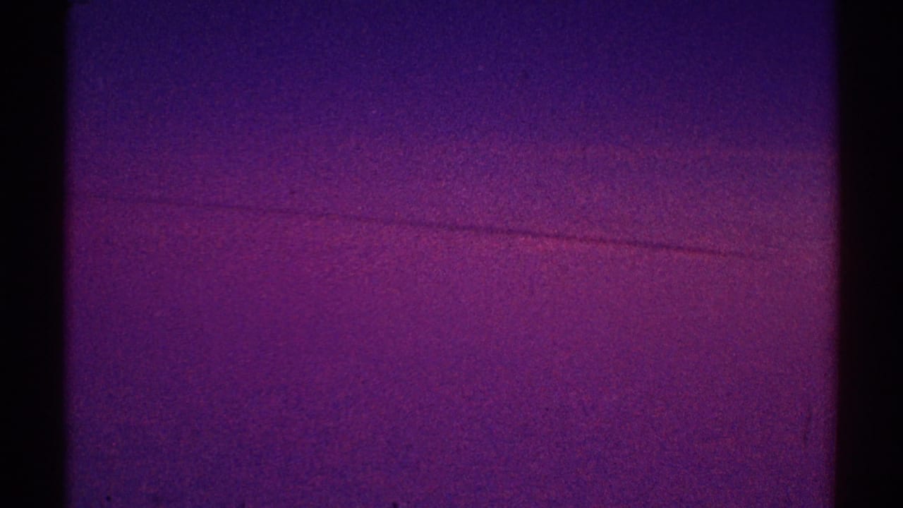 Purple and magenta sky with faint horizontal cloud band and dark film borders.