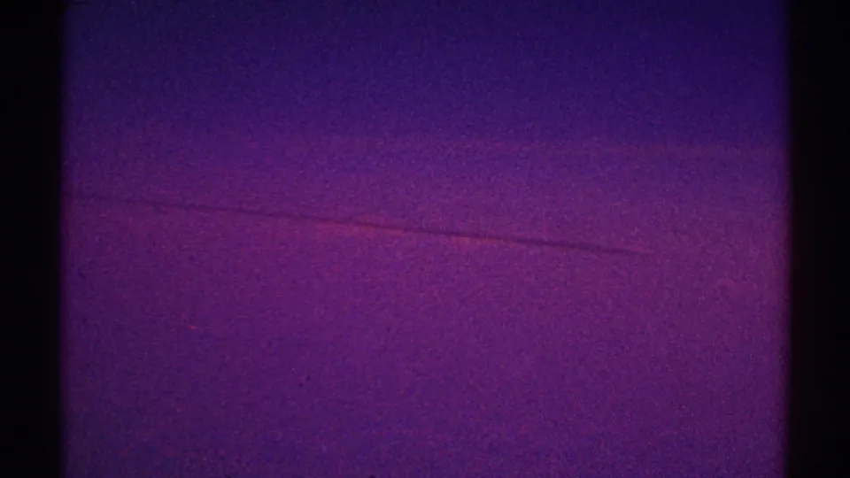 1969 Los Angeles home-movie still with violet and magenta sky tones, a thin horizontal mark, and heavy 8mm grain.