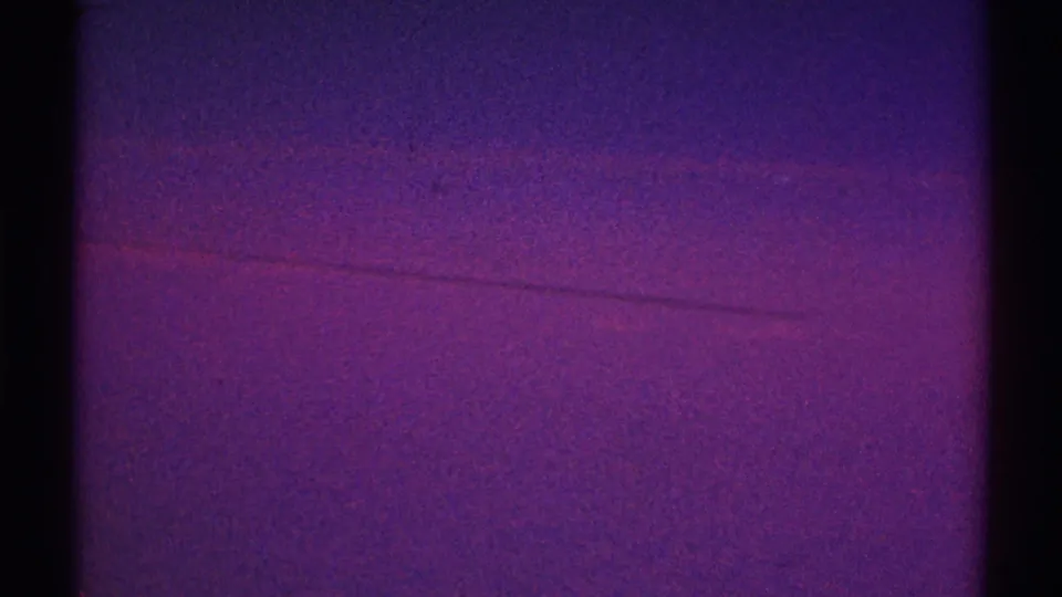 1969 Los Angeles home-movie frame with purple twilight color, faint magenta cloud streaks, and pronounced film grain.