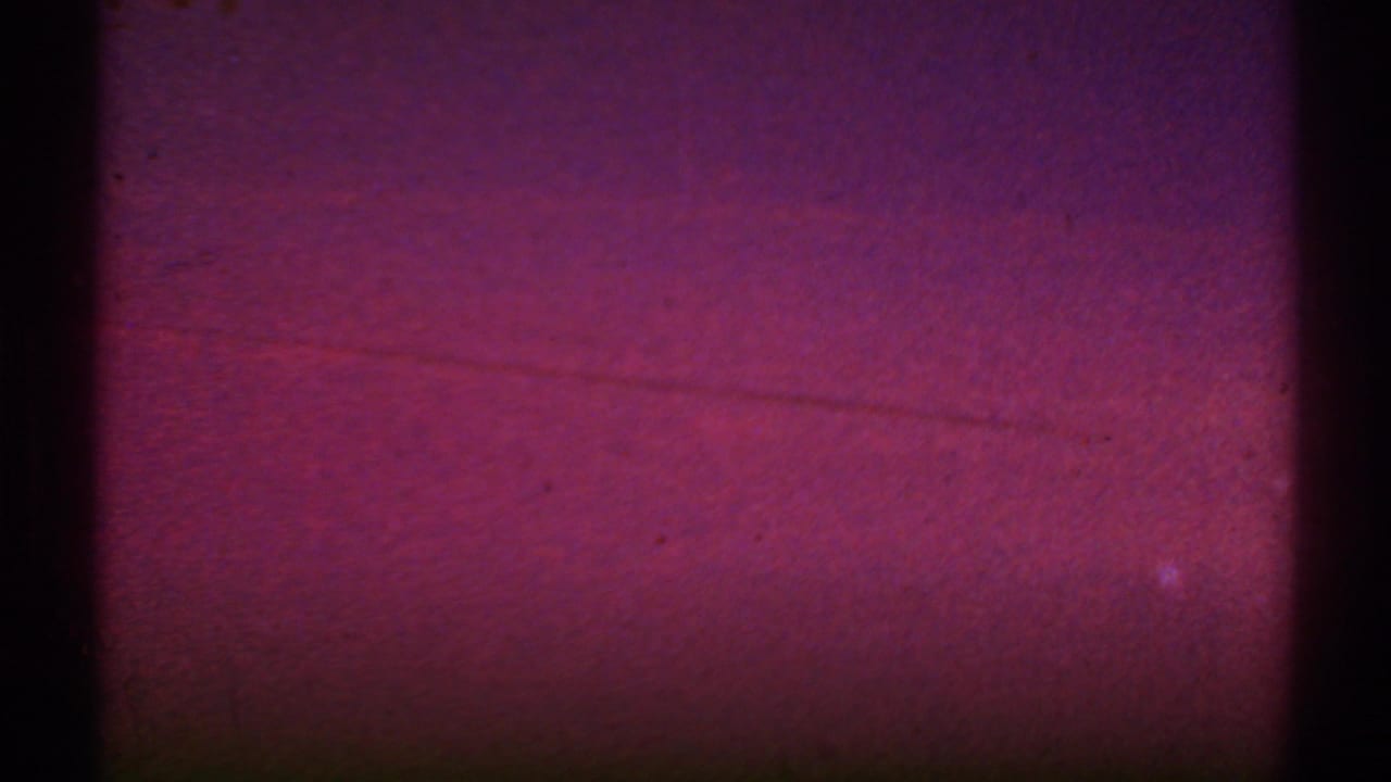 Reddish exposed film frame with dark gate edges and little visible scene detail.
