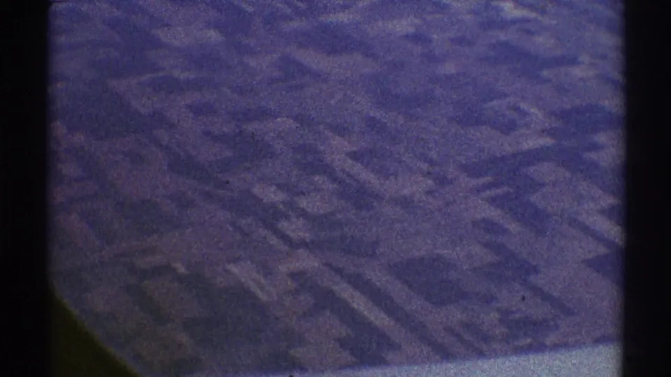 1969 Los Angeles-area 8mm aerial frame showing patchwork farmland and field divisions under a faded blue-purple cast.