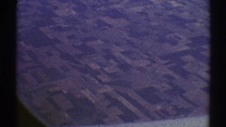 1969 Los Angeles-area aerial farmland view with rectangular plots, muted brown and green tones, and visible aged 8mm texture.