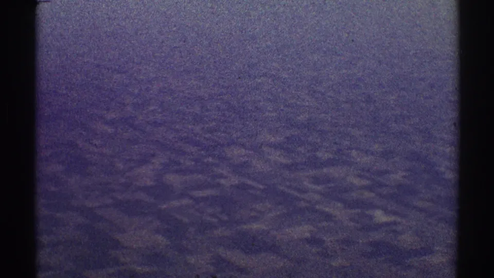 Late-1960s 8mm aerial view over indistinct landscape near Los Angeles, with faded color, grain, and a dark vertical frame edge.