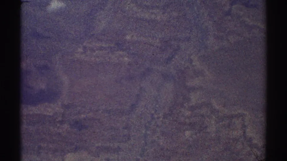 High-angle 8mm view over indistinct Los Angeles-area terrain, with haze, grain, and dark frame edges.