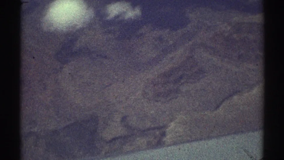 1969 Los Angeles-area aerial view with a bright reflection over grainy, purple-toned terrain.