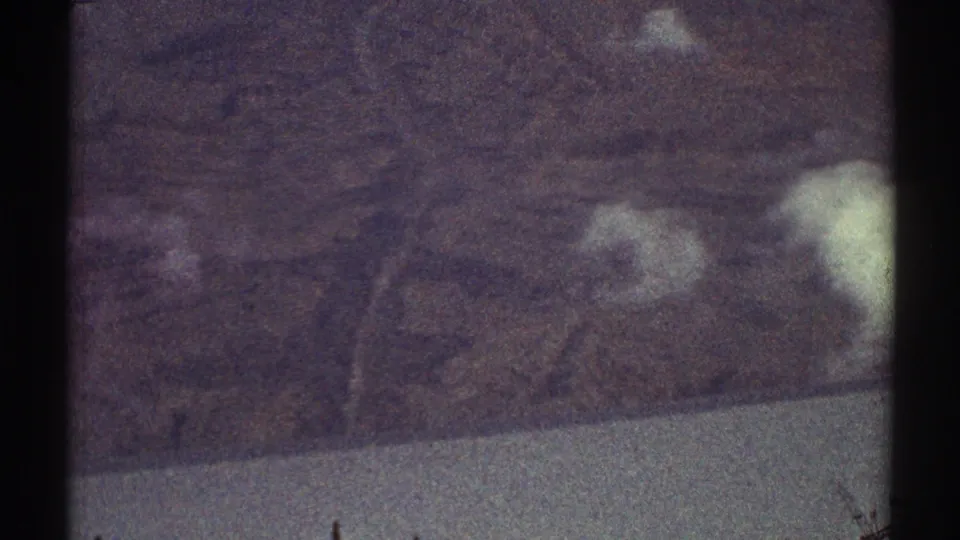 Los Angeles-area 1969 8mm aerial frame with muted hills, drifting white clouds, and visible film borders.